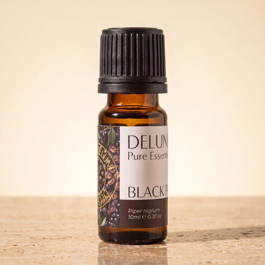 Delune Black Pepper Pure Essential Oil, 10ml amber glass bottle on warm travertine stone