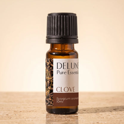 Delune Clove Pure Essential Oil, 10ml amber glass bottle on warm travertine stone