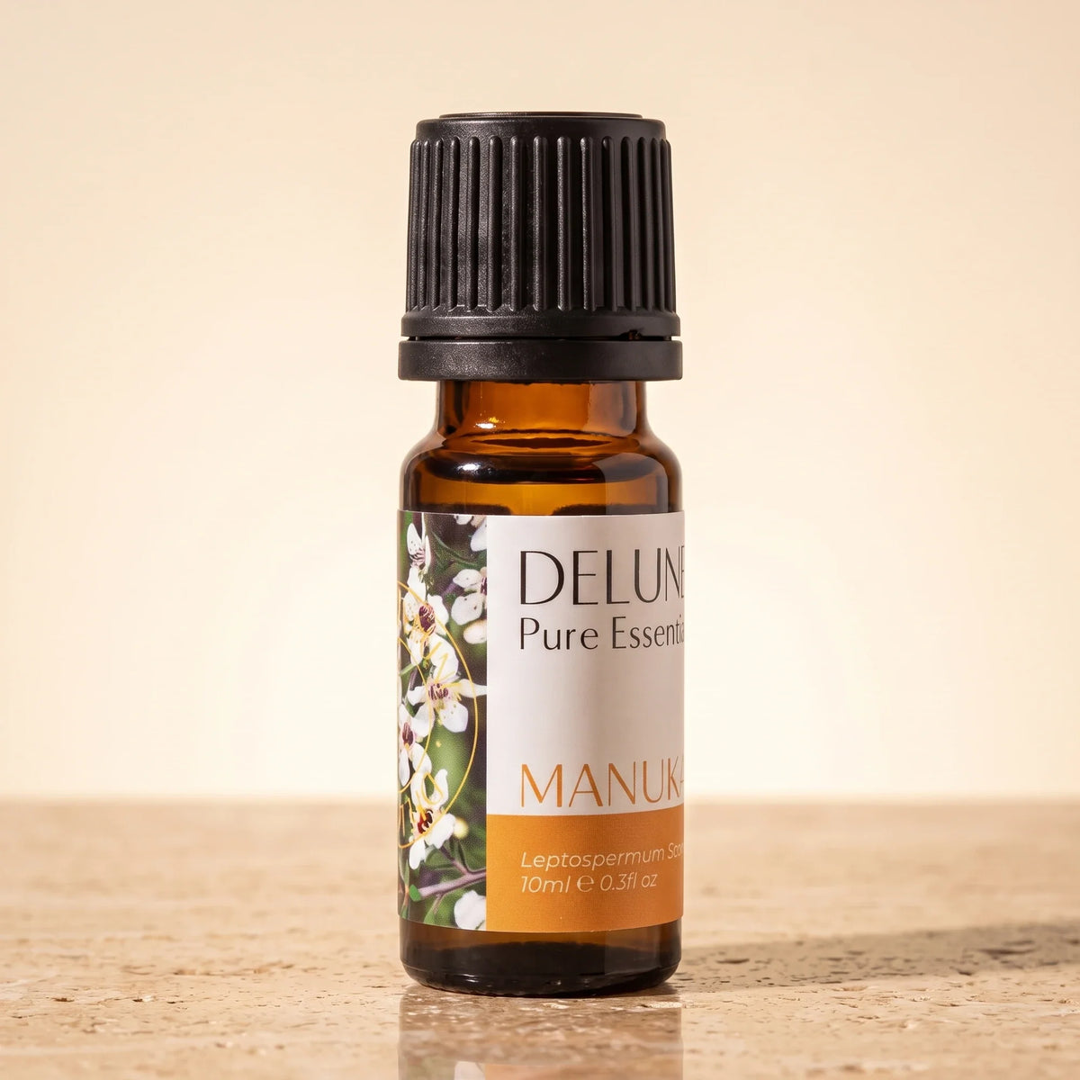 Delune Mānuka Pure Essential Oil, 10ml amber glass bottle on warm travertine stone